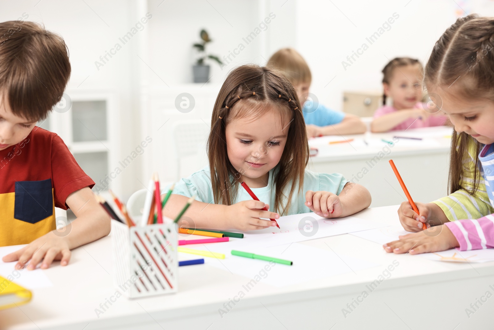 Photo of Group of children drawing at table indoors