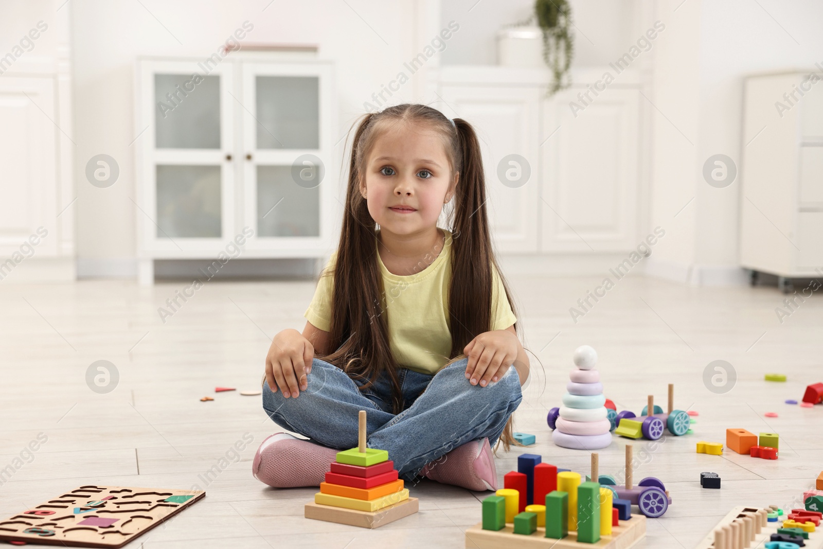 Photo of Cute little girl playing on floor indoors