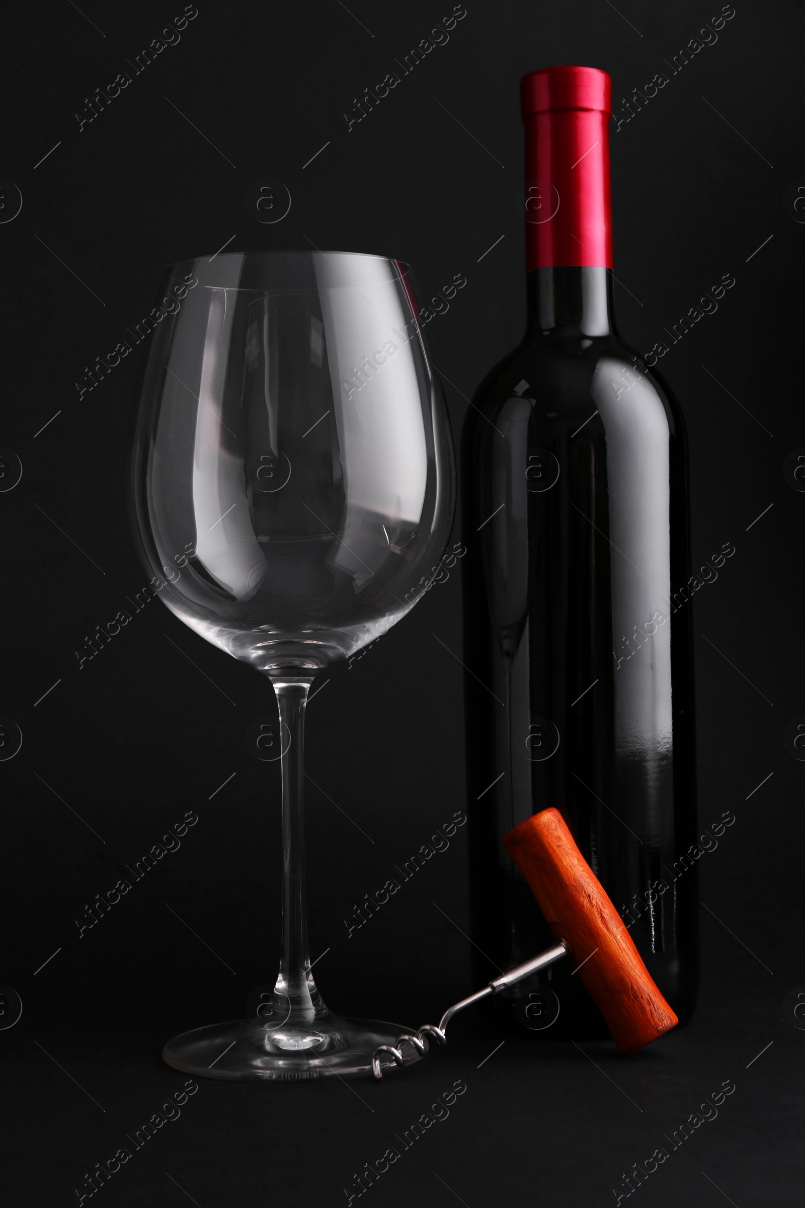 Photo of Bottle of wine, corkscrew and glass on dark background