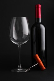 Photo of Bottle of wine, corkscrew and glass on dark background