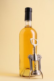 Photo of Wing corkscrew and bottle of wine on beige background