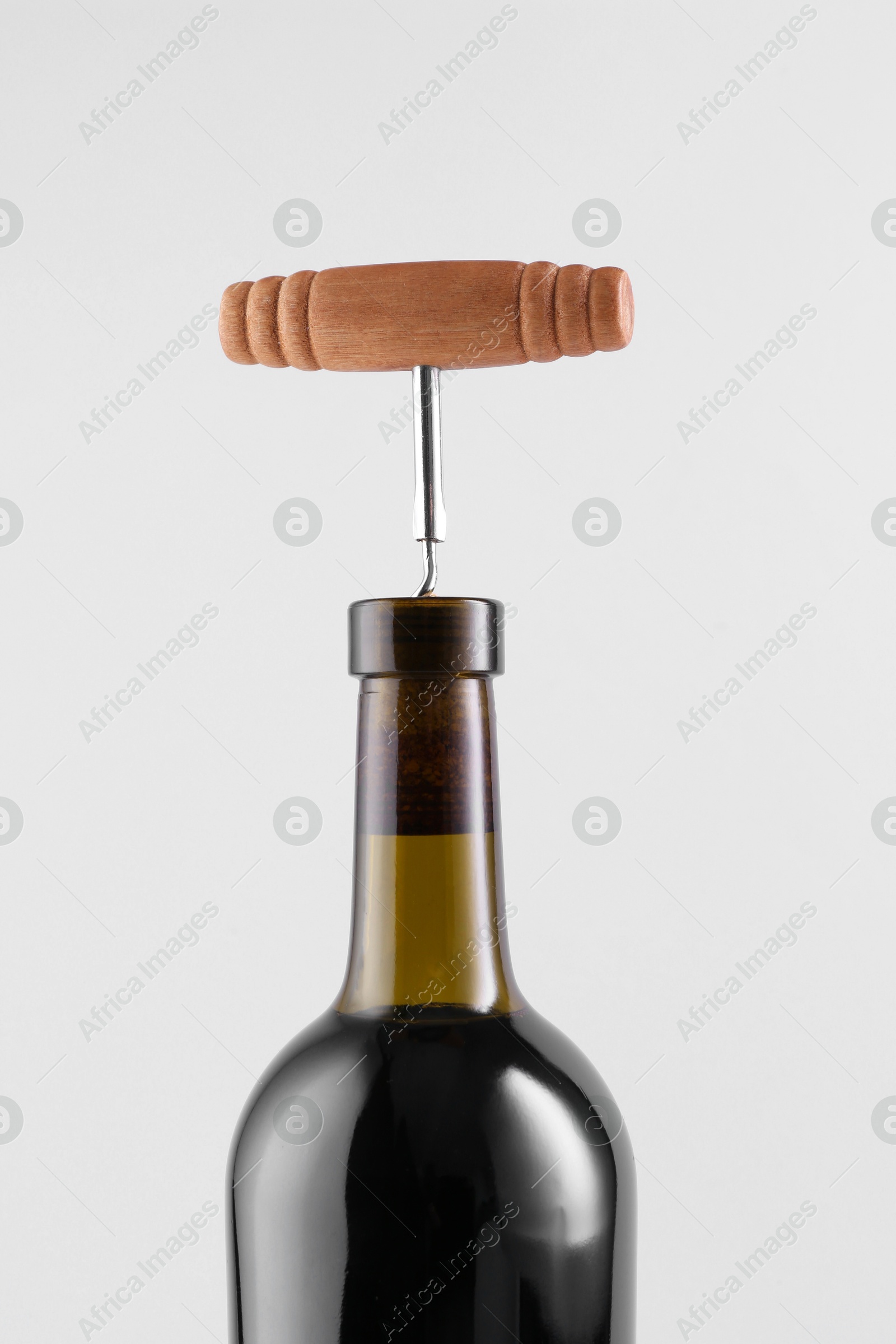 Photo of Wine bottle with corkscrew on light grey background