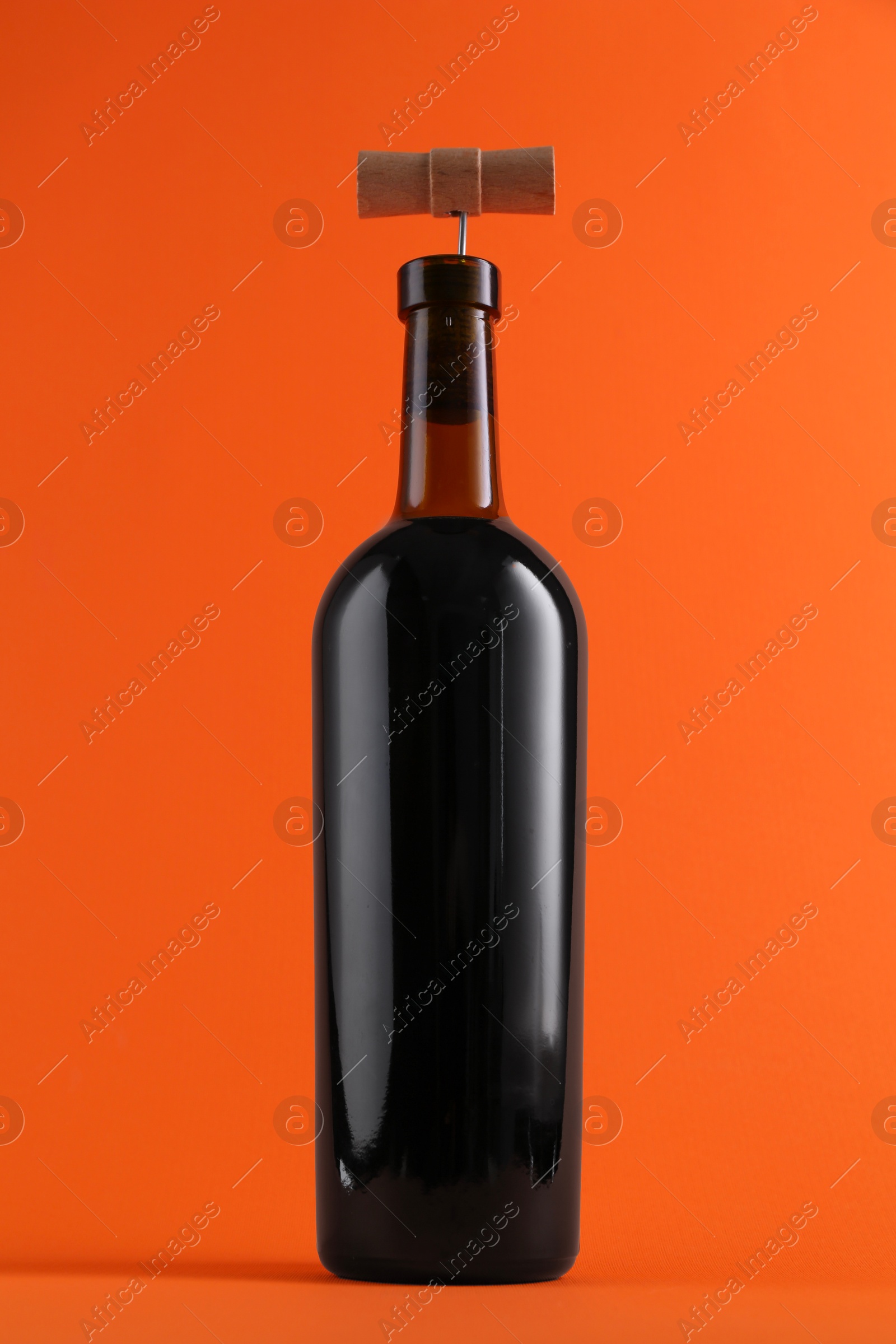 Photo of Wine bottle with corkscrew on orange background