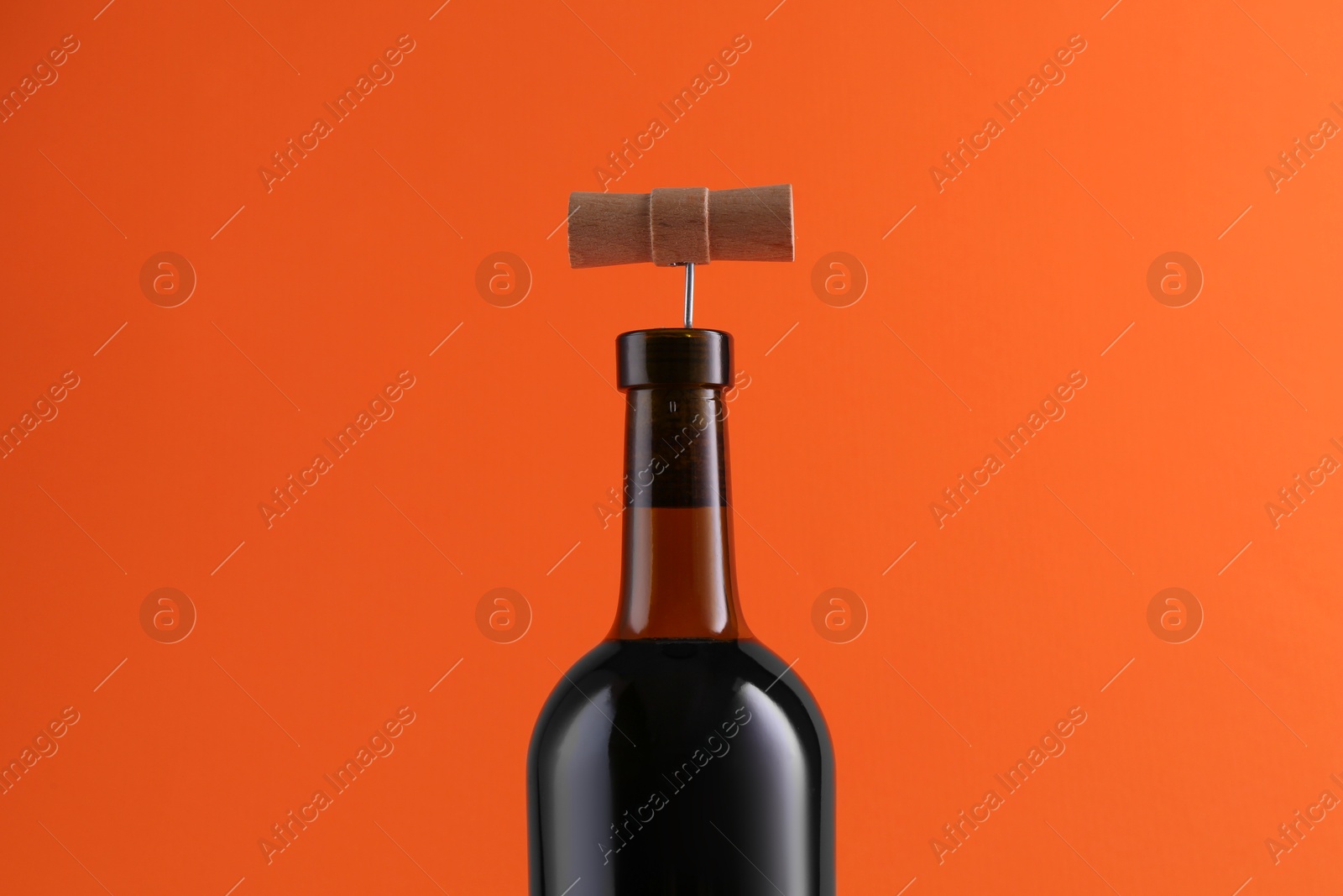 Photo of Wine bottle with corkscrew on orange background