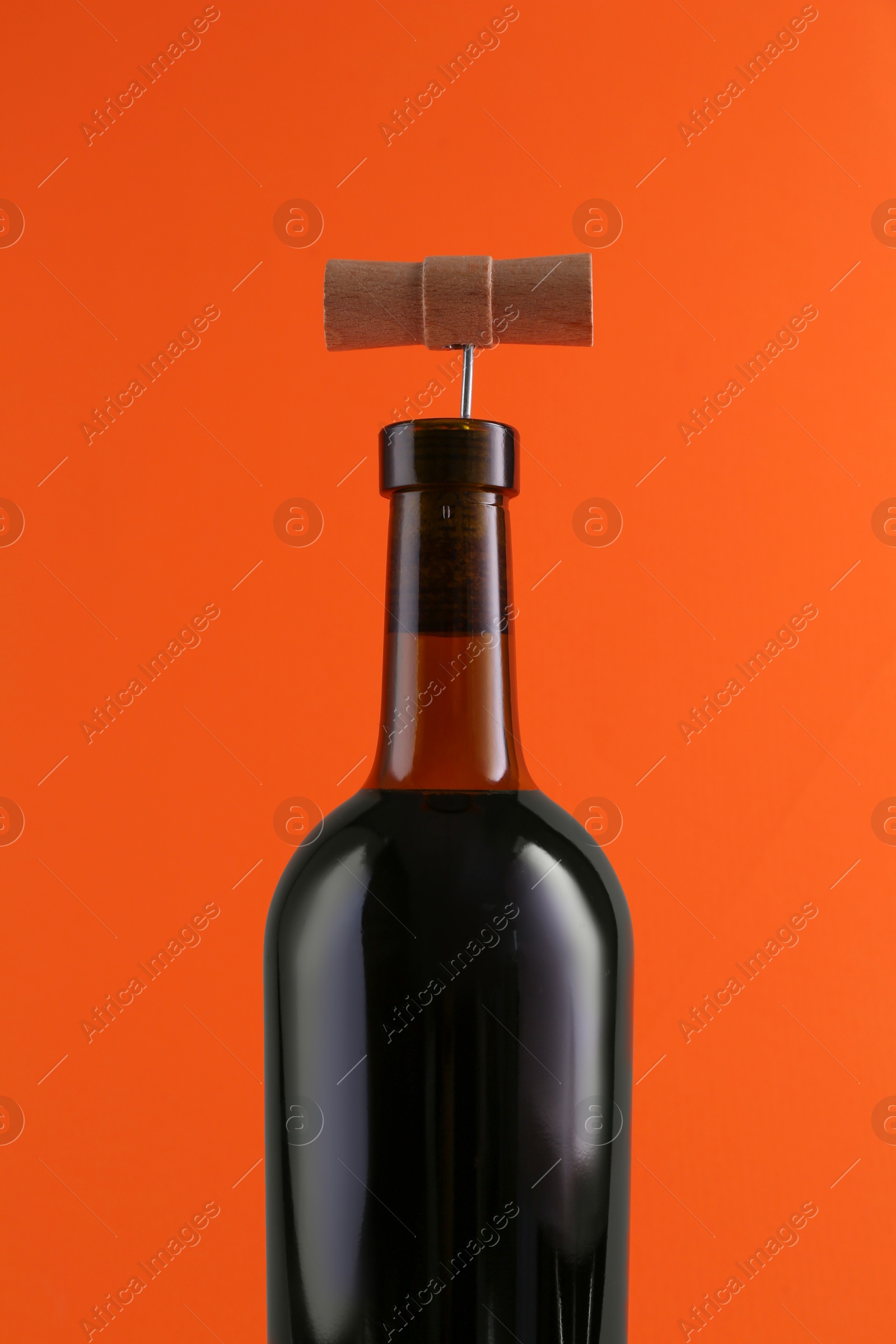 Photo of Wine bottle with corkscrew on orange background