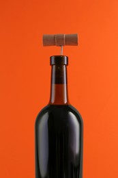 Photo of Wine bottle with corkscrew on orange background