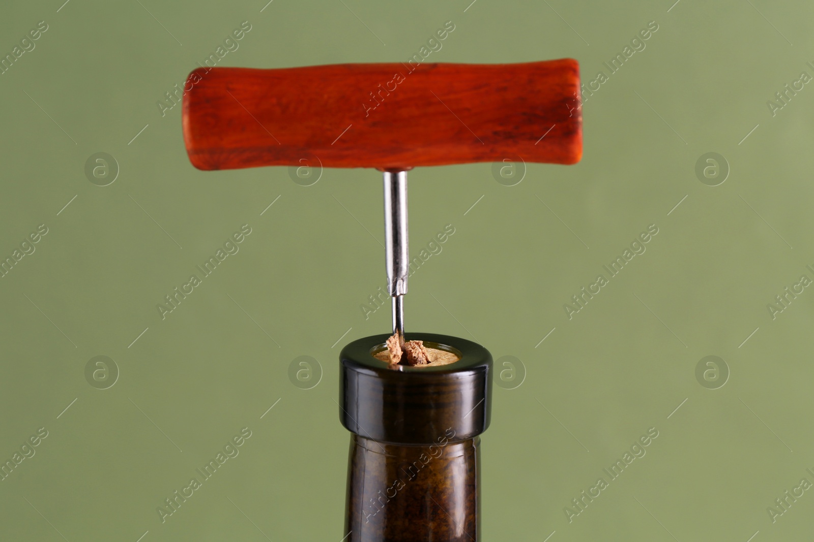 Photo of Wine bottle with corkscrew on olive background, closeup