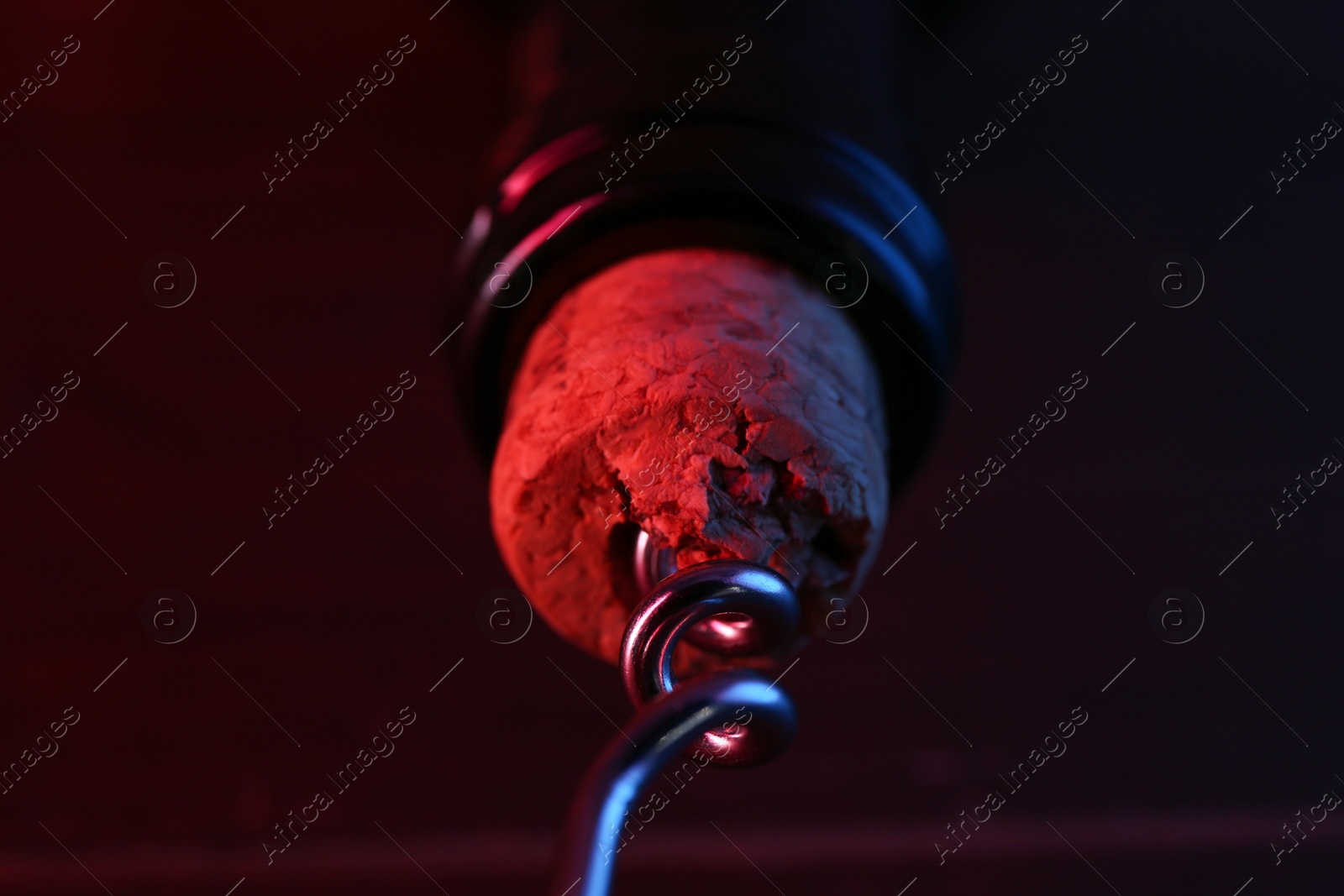 Photo of Wine bottle with corkscrew in lights on table, closeup