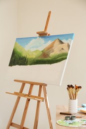 Photo of Easel with beautiful landscape in drawing studio. Unfinished artwork