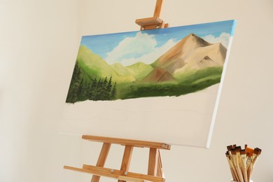 Easel with beautiful landscape in drawing studio. Unfinished artwork