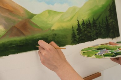 Photo of Woman drawing landscape with brush in studio, closeup