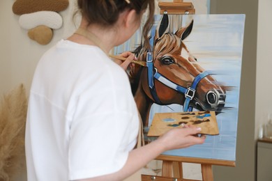 Woman drawing cute horse with brush in studio, closeup