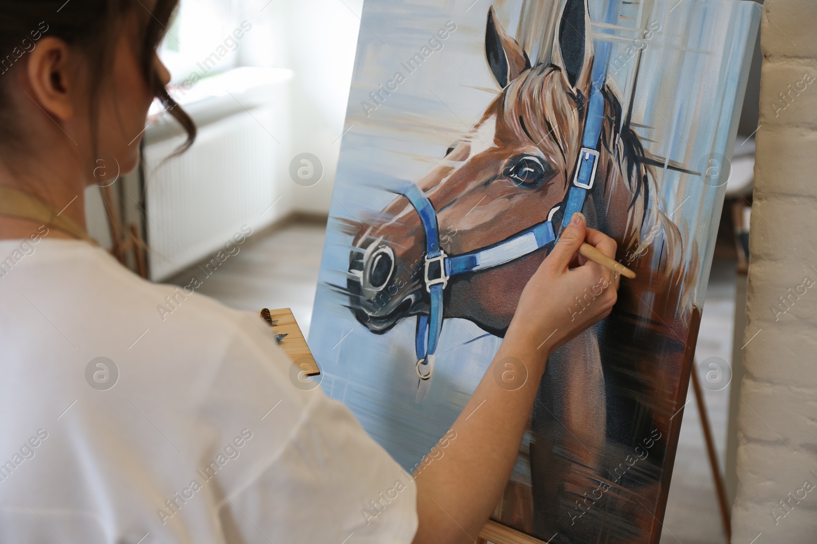 Photo of Woman drawing cute horse with brush in studio, closeup