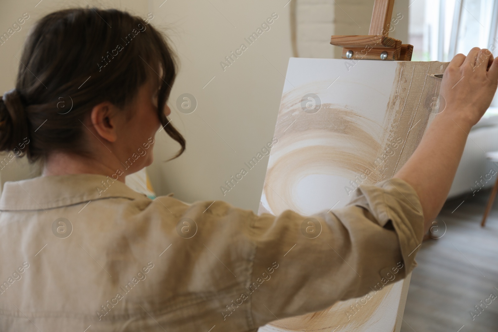 Photo of Woman drawing on easel with canvas in studio