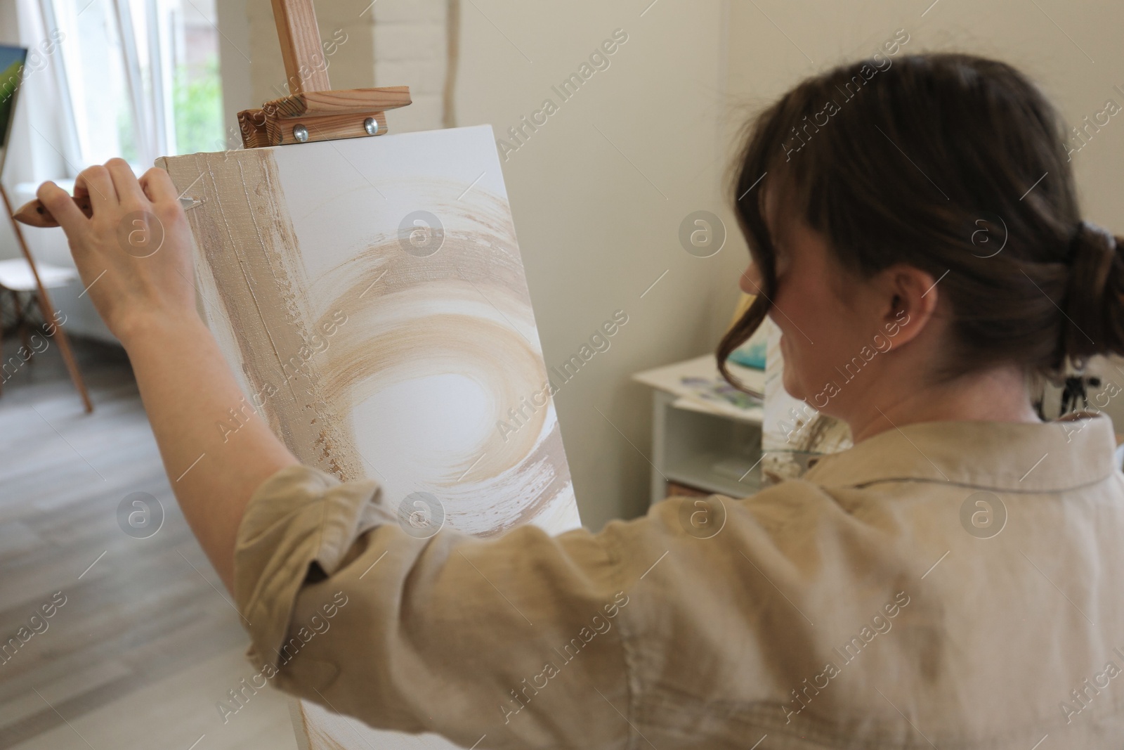 Photo of Woman drawing on easel with canvas in studio