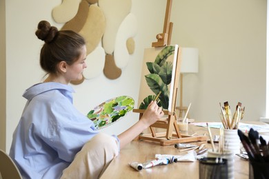 Woman with brush drawing picture at table in studio