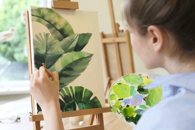 Woman with brush drawing picture in studio, closeup