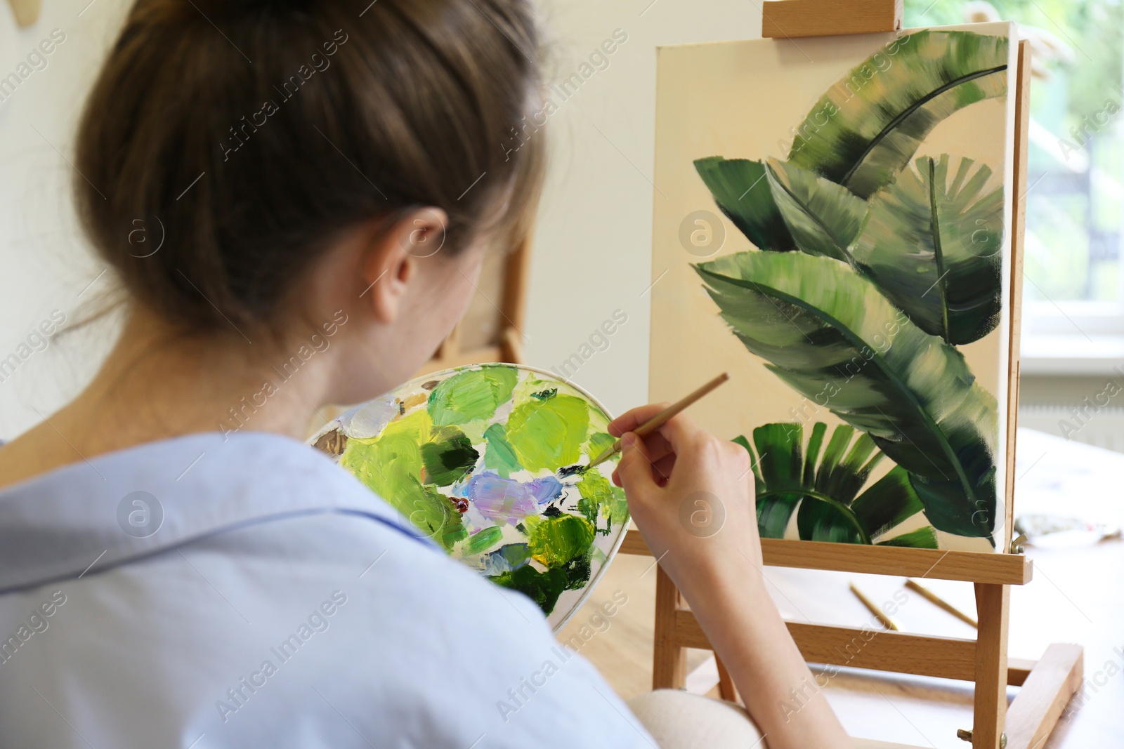 Photo of Woman with brush painting tropical leaves in studio