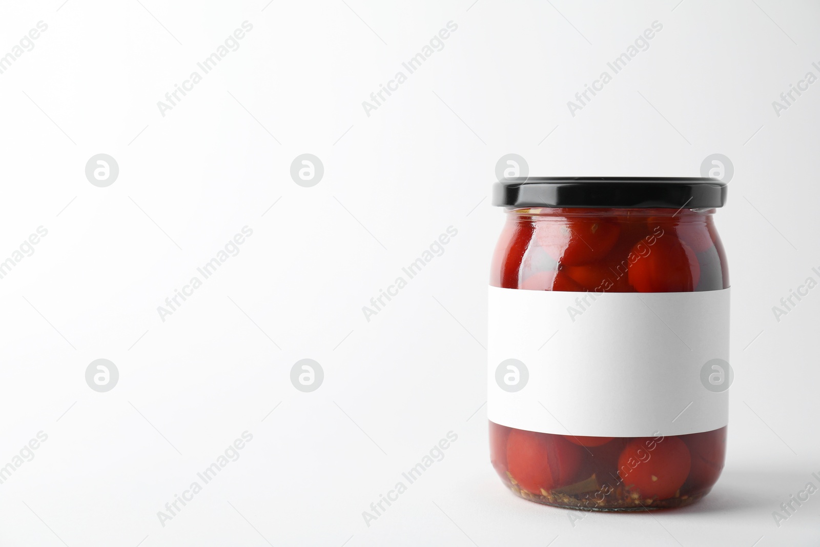 Photo of Tasty pickled tomatoes in jar on light background. Space for text