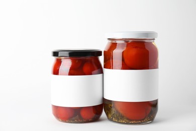 Tasty pickled tomatoes in jars on light background, closeup. Space for text