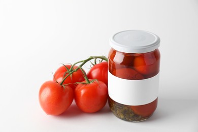 Tasty pickled tomatoes in jar and vegetables on light background