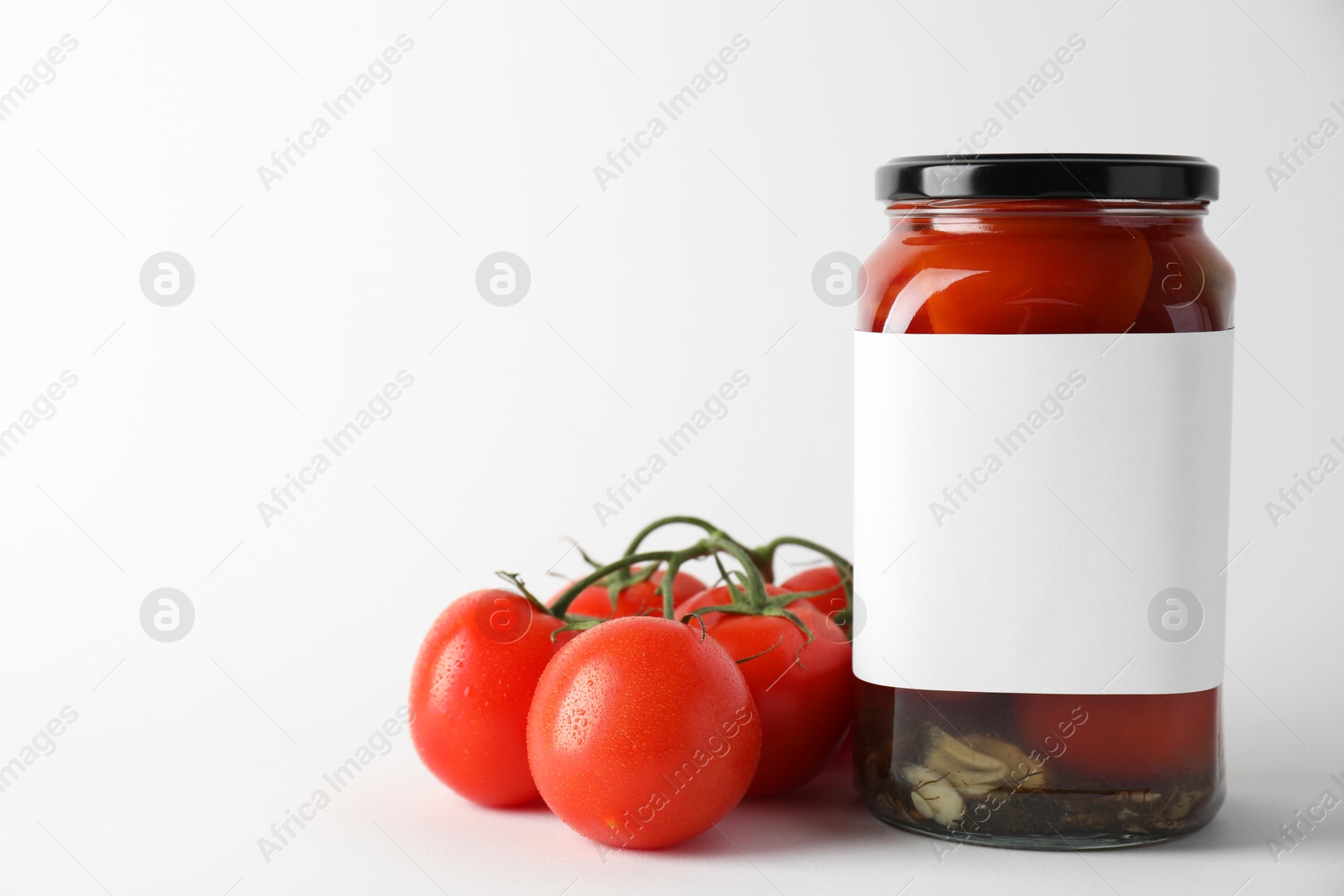 Photo of Tasty pickled tomatoes in jar and vegetables on light background, closeup. Space for text