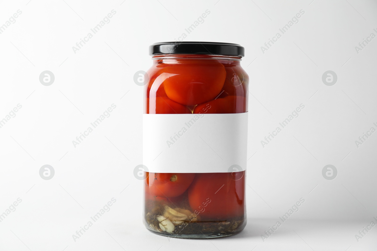 Photo of Tasty pickled tomatoes in jar on light background