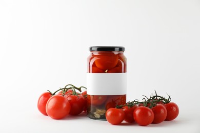 Tasty pickled tomatoes in jar and vegetables on light background