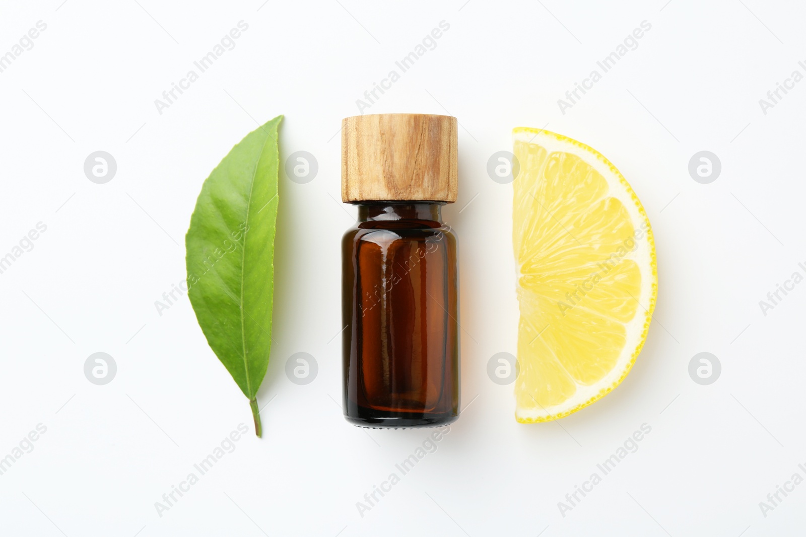 Photo of Bottle of essential oil, lemon and green leaf on white background, flat lay