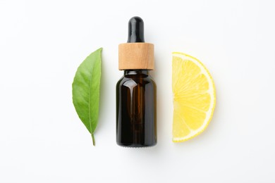 Bottle of essential oil, lemon and green leaf on white background, flat lay