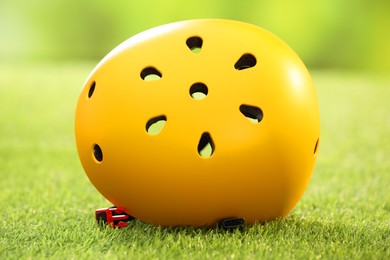 Photo of Yellow protective helmet on green grass, closeup