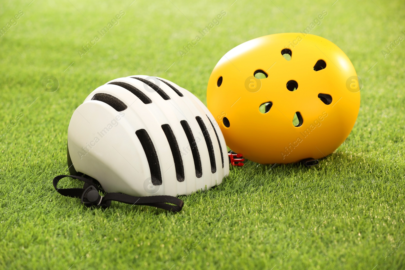 Photo of White and yellow protective helmets on green grass