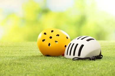 White and yellow protective helmets on green grass, space for text