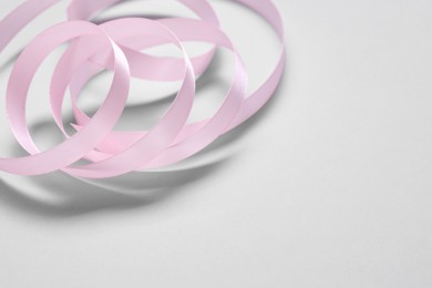 One beautiful pink ribbon on white background, space for text