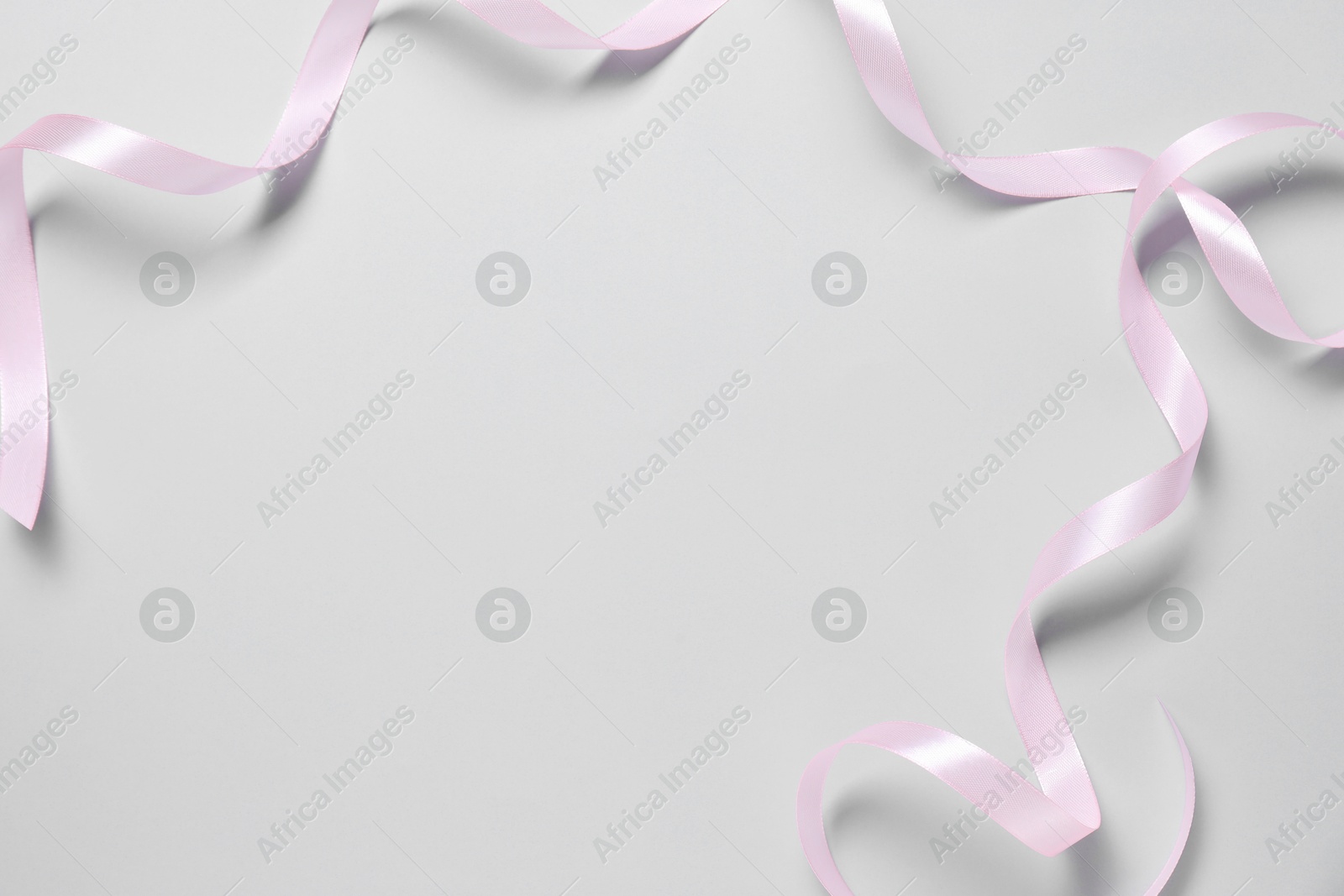 Photo of One beautiful pink ribbon on white background, top view. Space for text