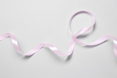 Photo of One beautiful pink ribbon on white background, top view