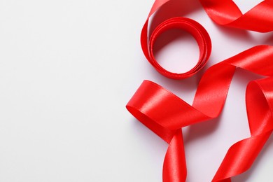 Photo of One beautiful red ribbon on white background, top view. Space for text