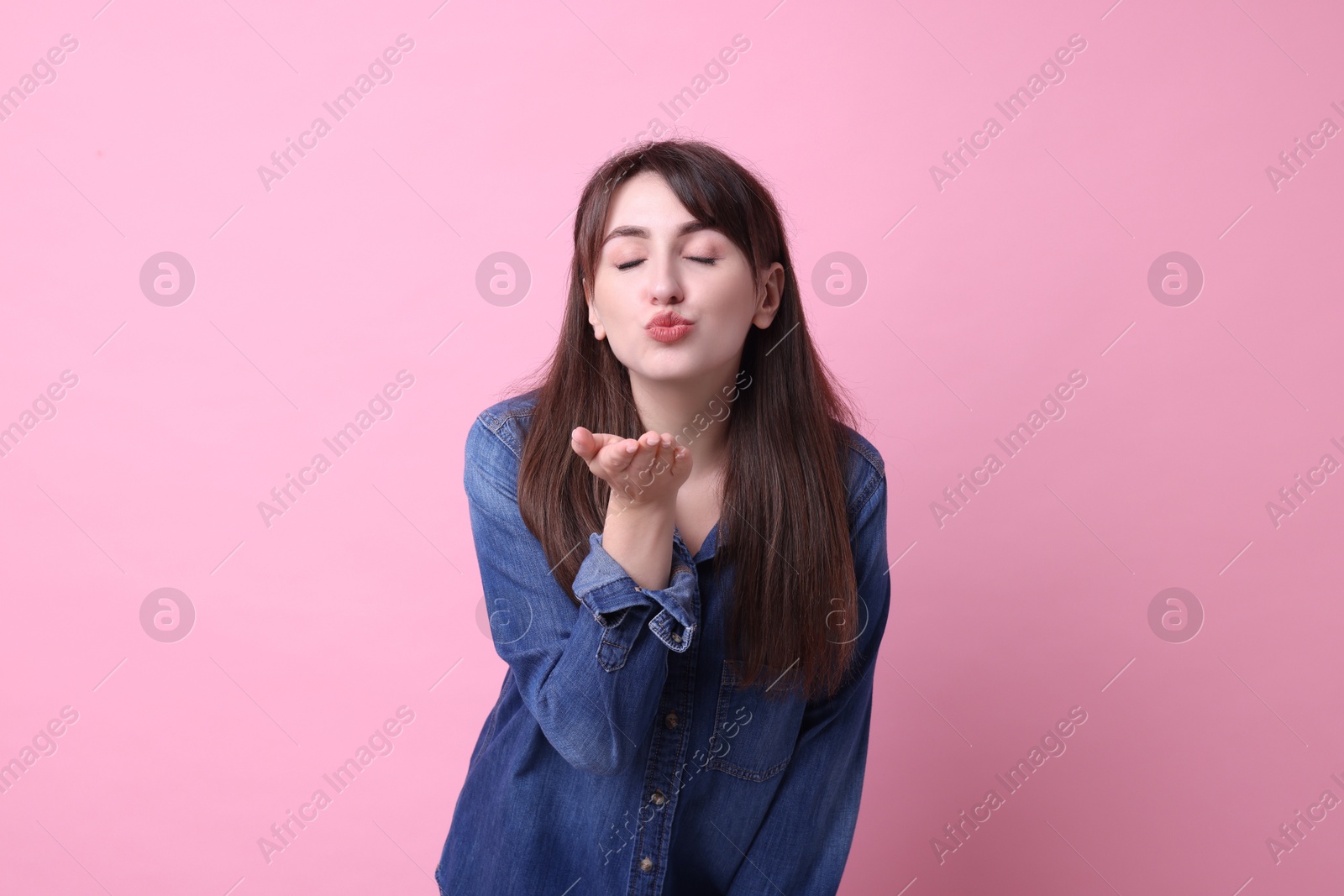 Photo of Beautiful woman blowing kiss on pink background