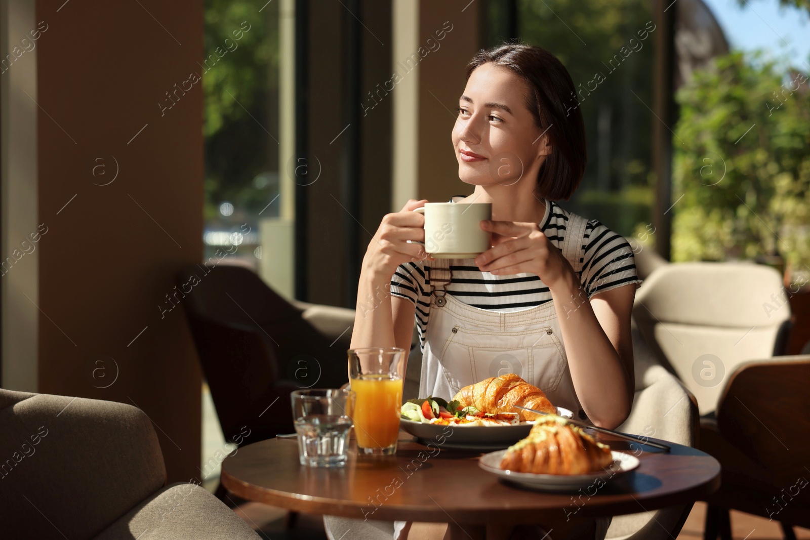 Photo of Happy woman having tasty breakfast in cafe, space for text