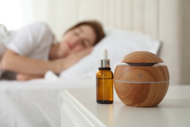 Photo of Woman sleeping at home, focus on aroma diffuser and essential oil