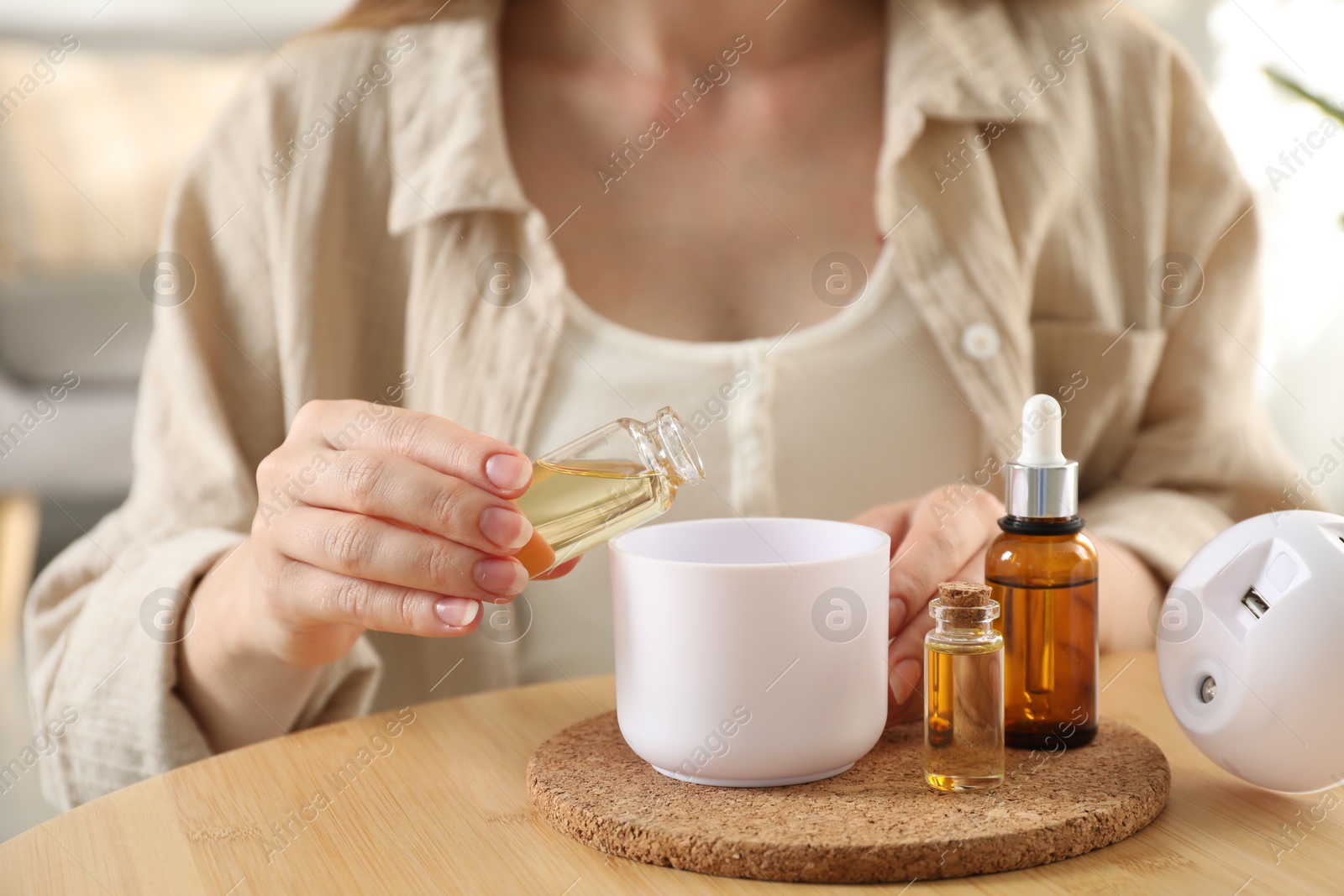 Photo of Woman adding essential oil to aroma diffuser at home, closeup