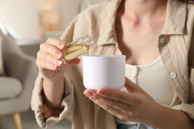 Photo of Woman adding essential oil to aroma diffuser at home, closeup