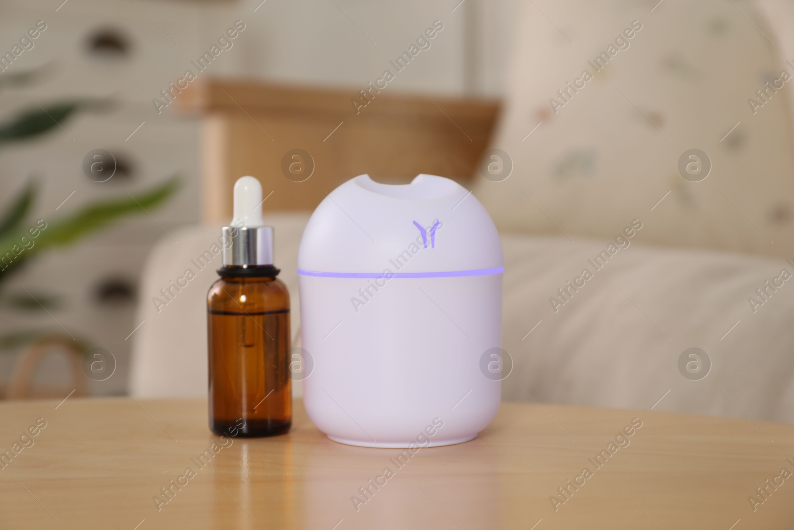 Photo of Aroma diffuser and bottle of essential oil on wooden table at home