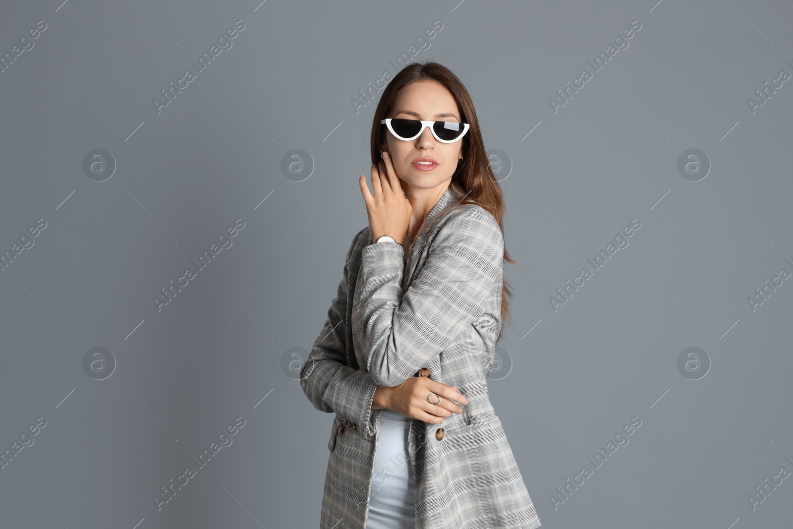 Photo of Beautiful woman with stylish jacket and sunglasses on grey background