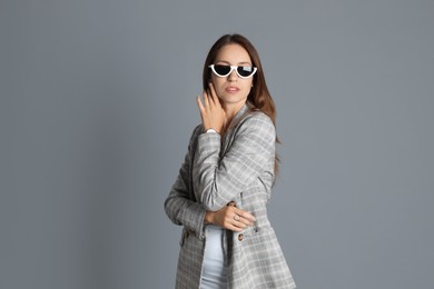 Photo of Beautiful woman with stylish jacket and sunglasses on grey background