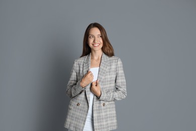 Beautiful woman in stylish jacket on grey background