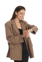 Beautiful woman in stylish brown jacket and black dress checking time on white background