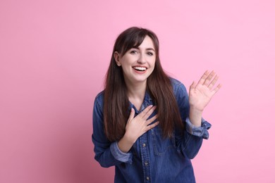 Photo of Happy young woman waving on pink background