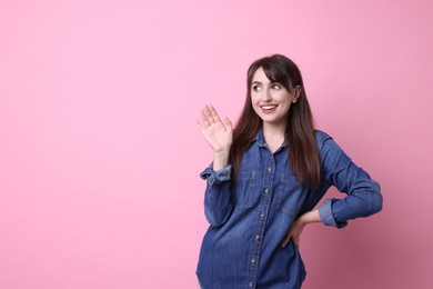 Photo of Happy young woman waving on pink background, space for text