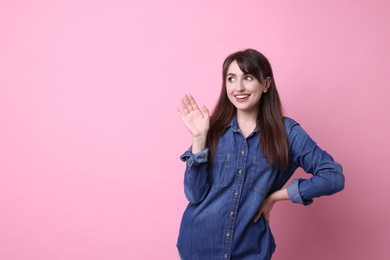 Happy young woman waving on pink background, space for text